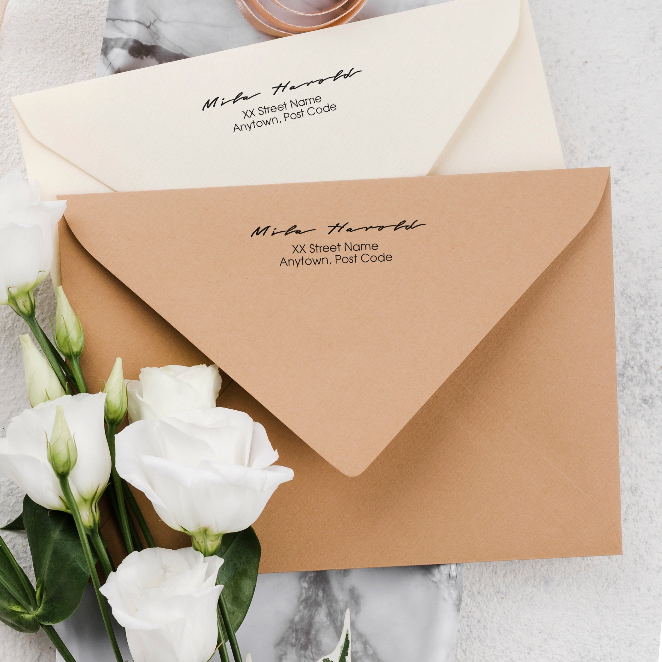 Custom address stamp on envelopes with white roses, showcasing traditional and elegant design for wedding invitations.