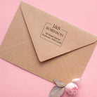 Custom return address stamp on a kraft envelope with floral accents.