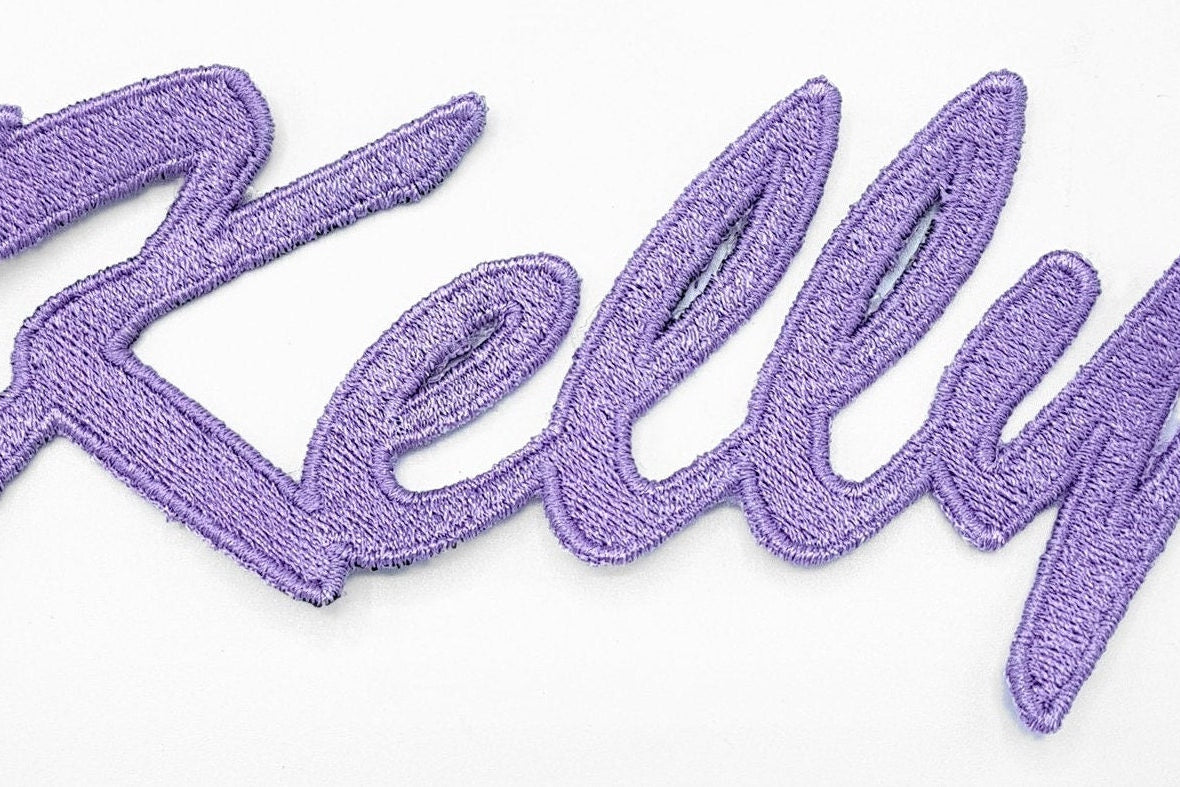 Embroidered personalized name patch with the name 'Kelly' in vibrant purple thread.