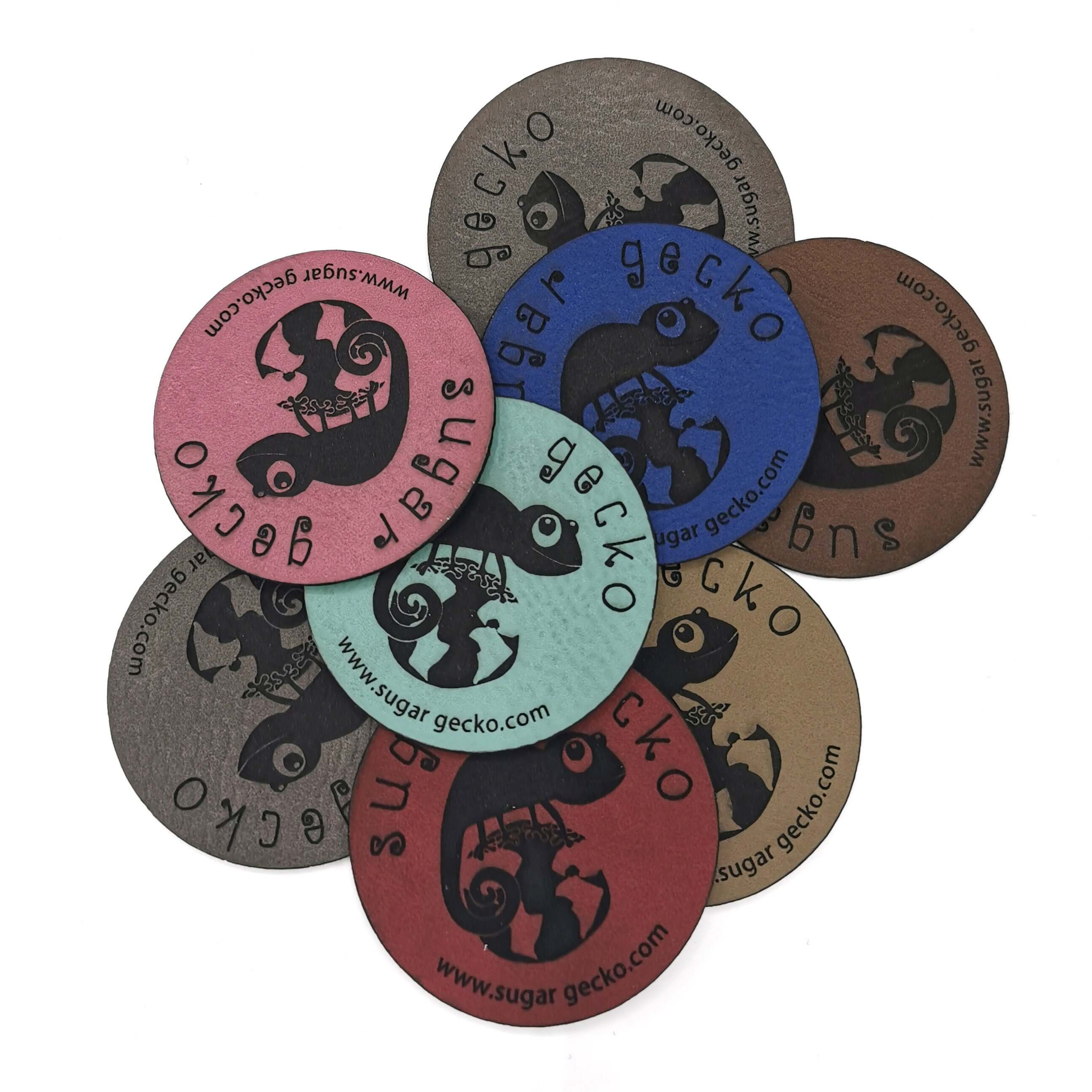 Collection of custom engraved leather patches in various colors with sugar gecko logo.