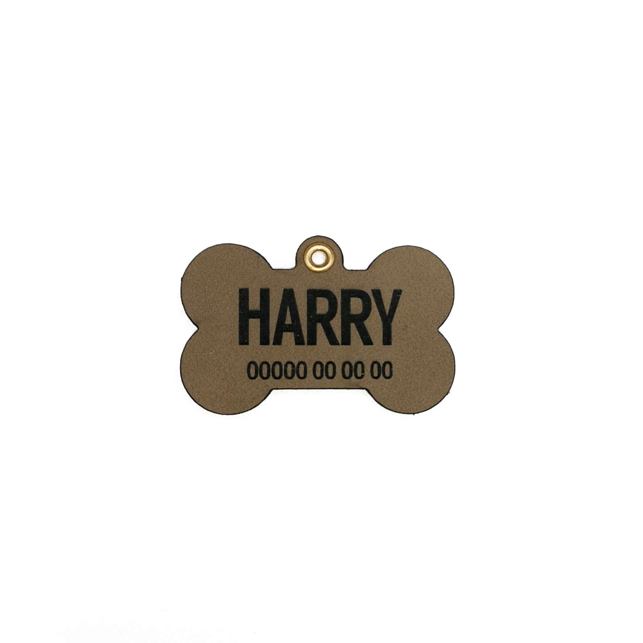 Personalised leather dog name tag in bone shape engraved with 'HARRY' and contact details.