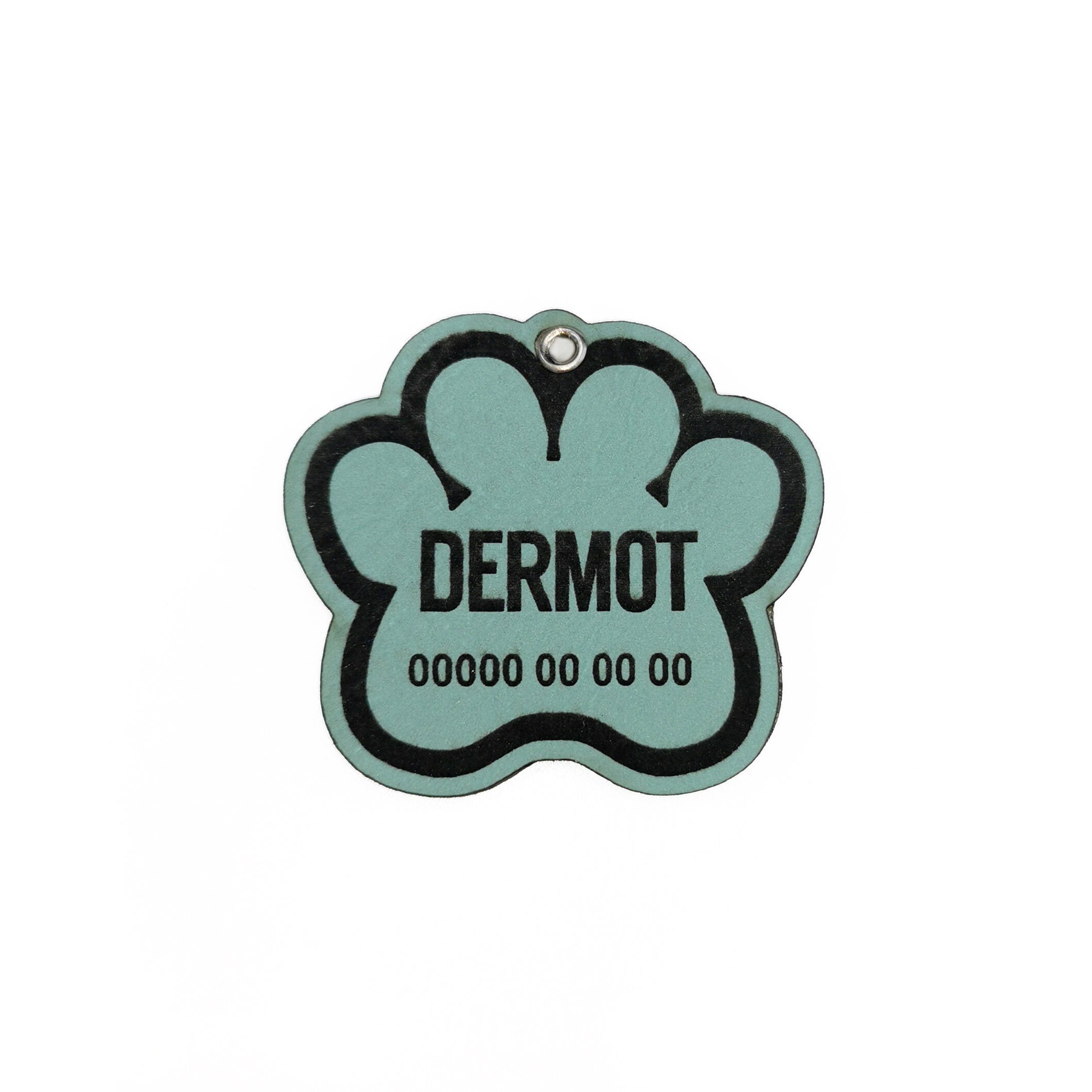 Custom leather dog tag with paw design, engraved with name Dermot and contact info.