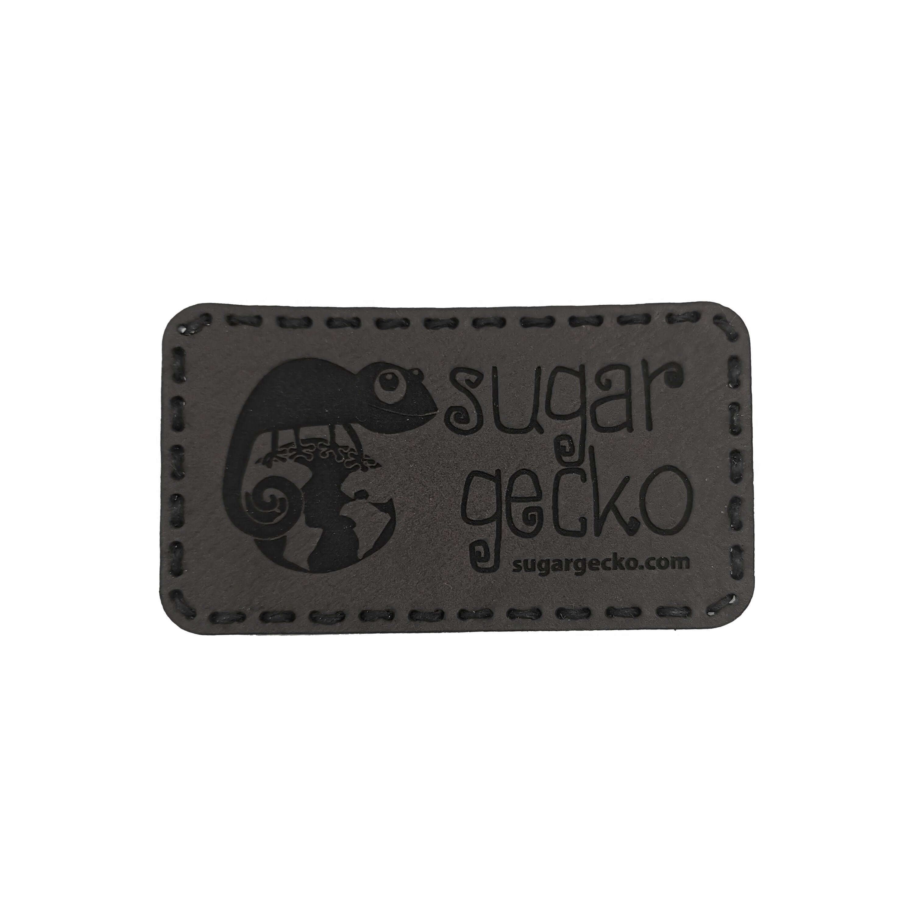 Custom engraved leather patch featuring a gecko design and the text 'sugar gecko' on a dark background.