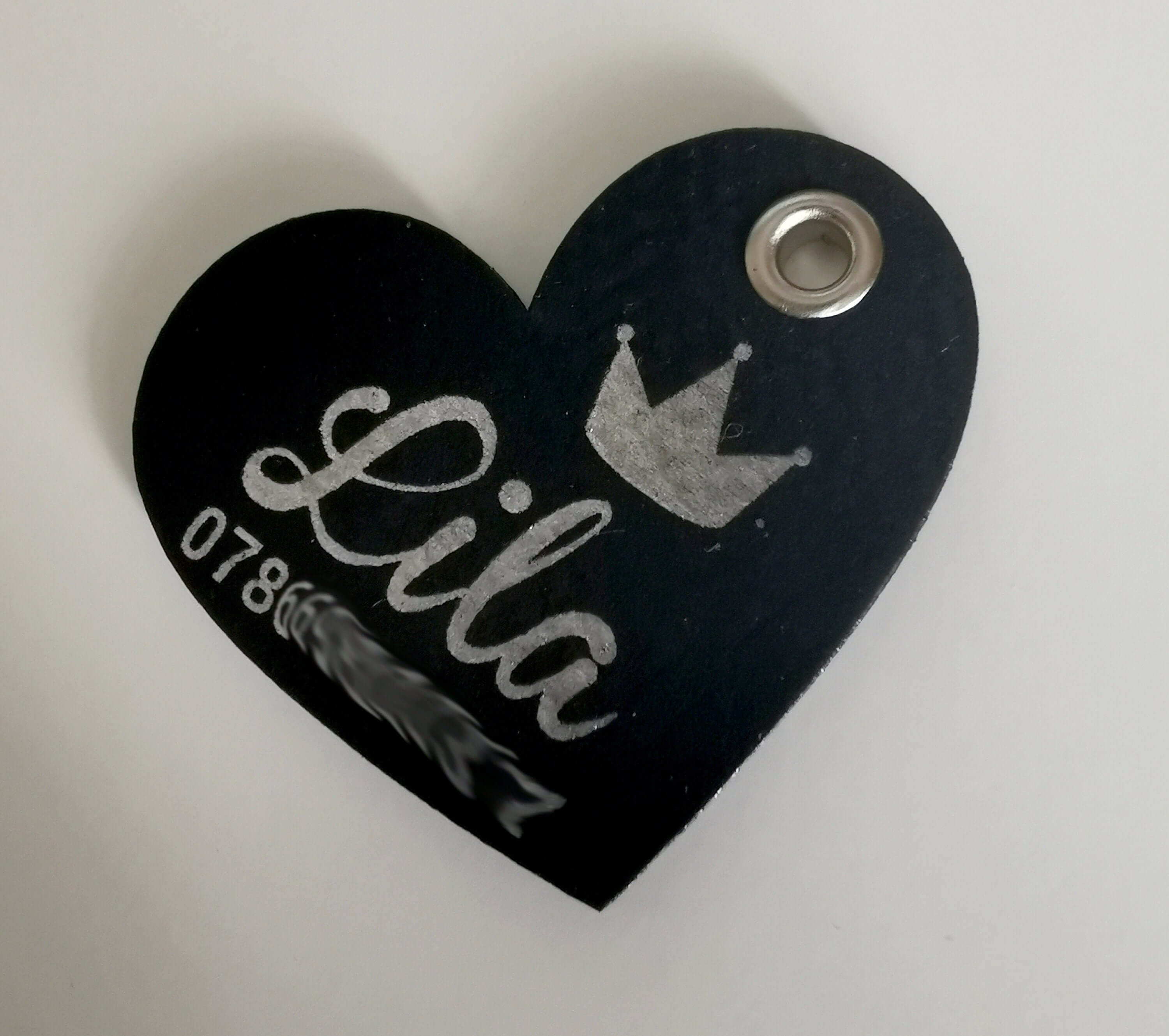 Personalized heart-shaped leather dog name tag engraved with the name 'Lila' and a crown design.