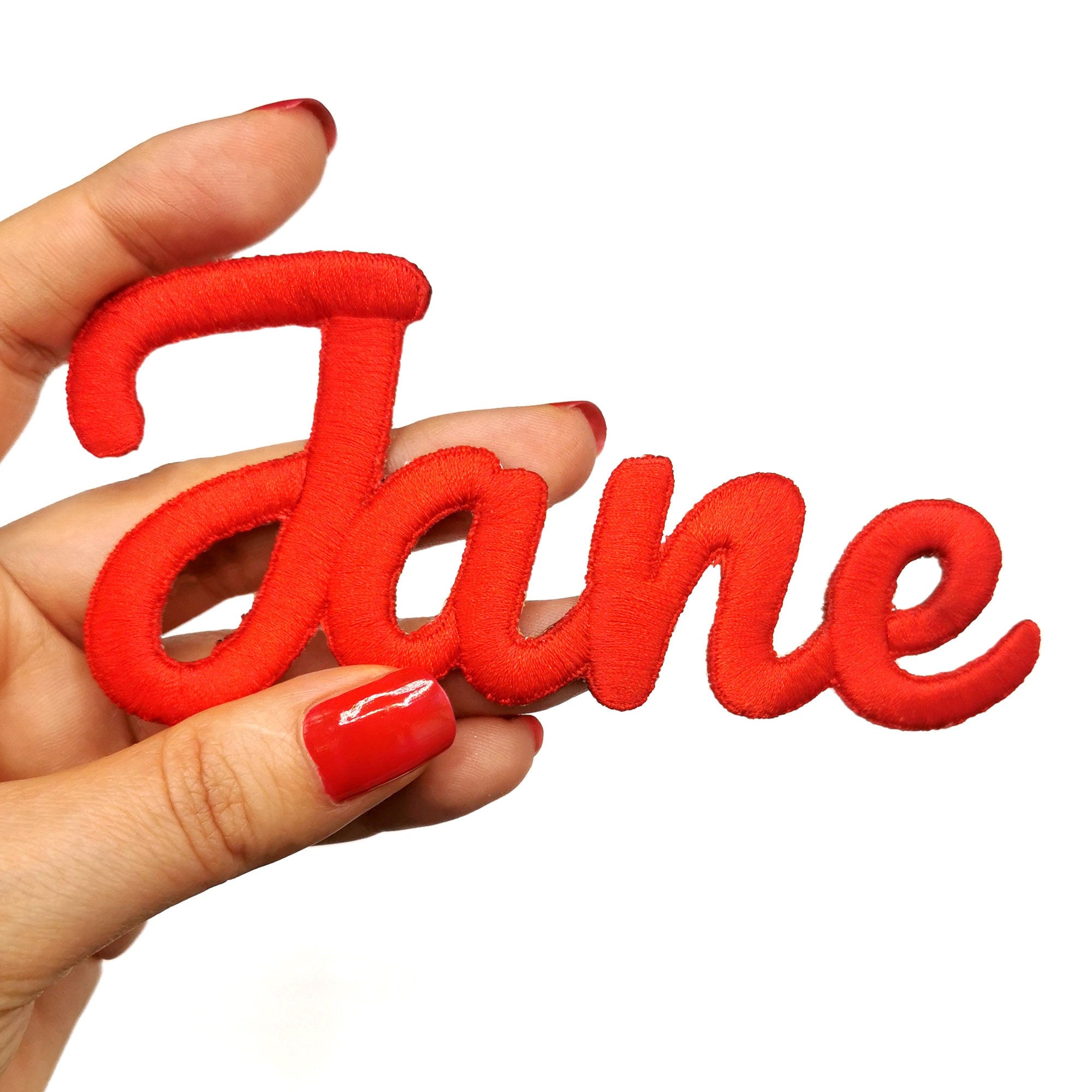 Red embroidered name patch reading 'Jane', held by a hand, showcasing personalized appliqué design.