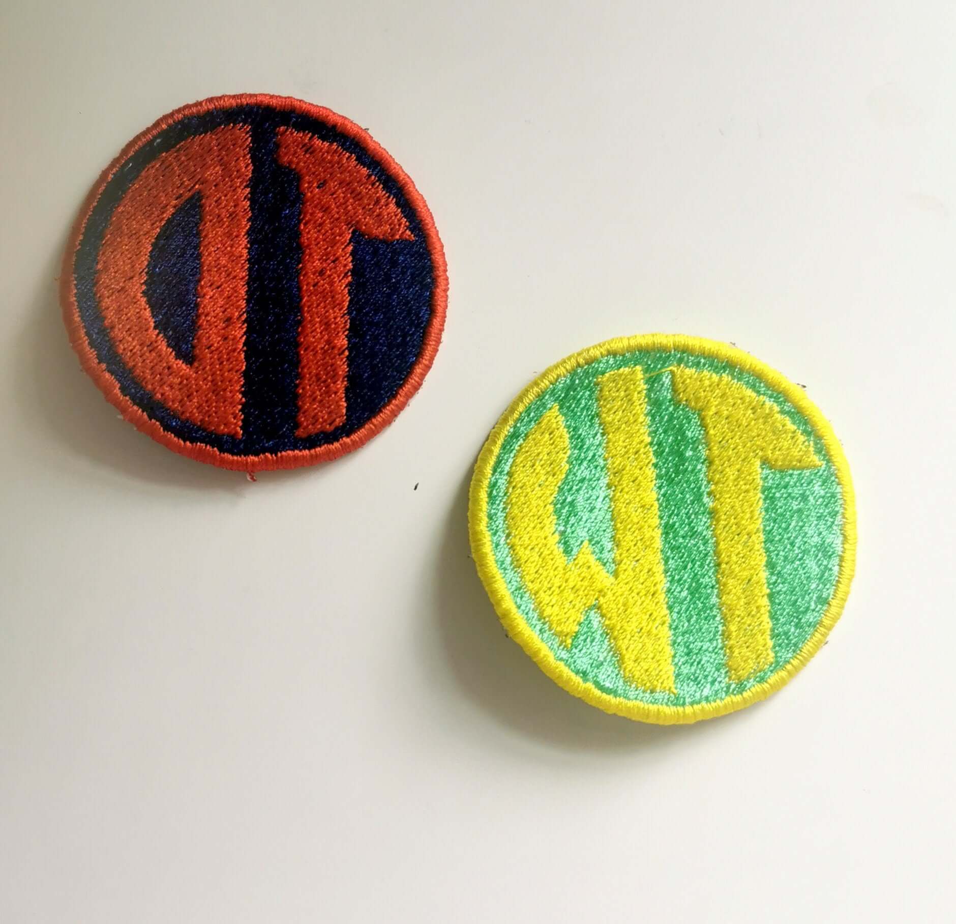 Custom embroidered circle monogram patches in red and yellow; ideal for personalizing bags and clothing.