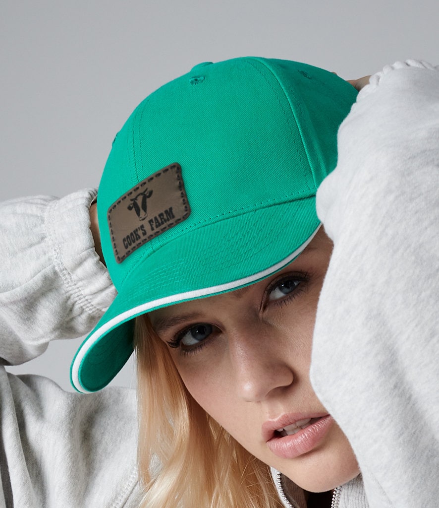 Custom leather patch cap in vibrant teal, styled with a cozy gray sweatshirt, showcasing personalized design.