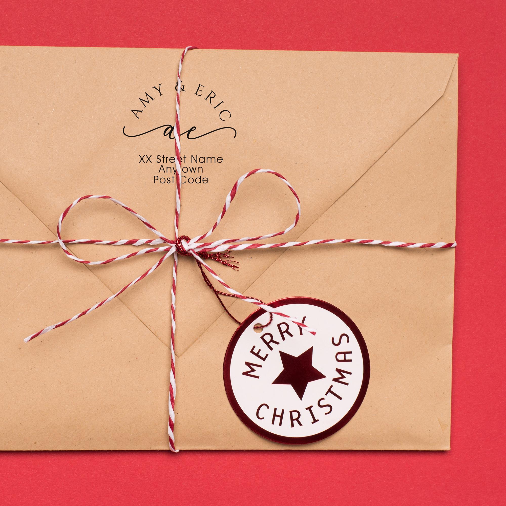 Customizable address stamp on a kraft envelope with a 'Merry Christmas' gift tag and twine.