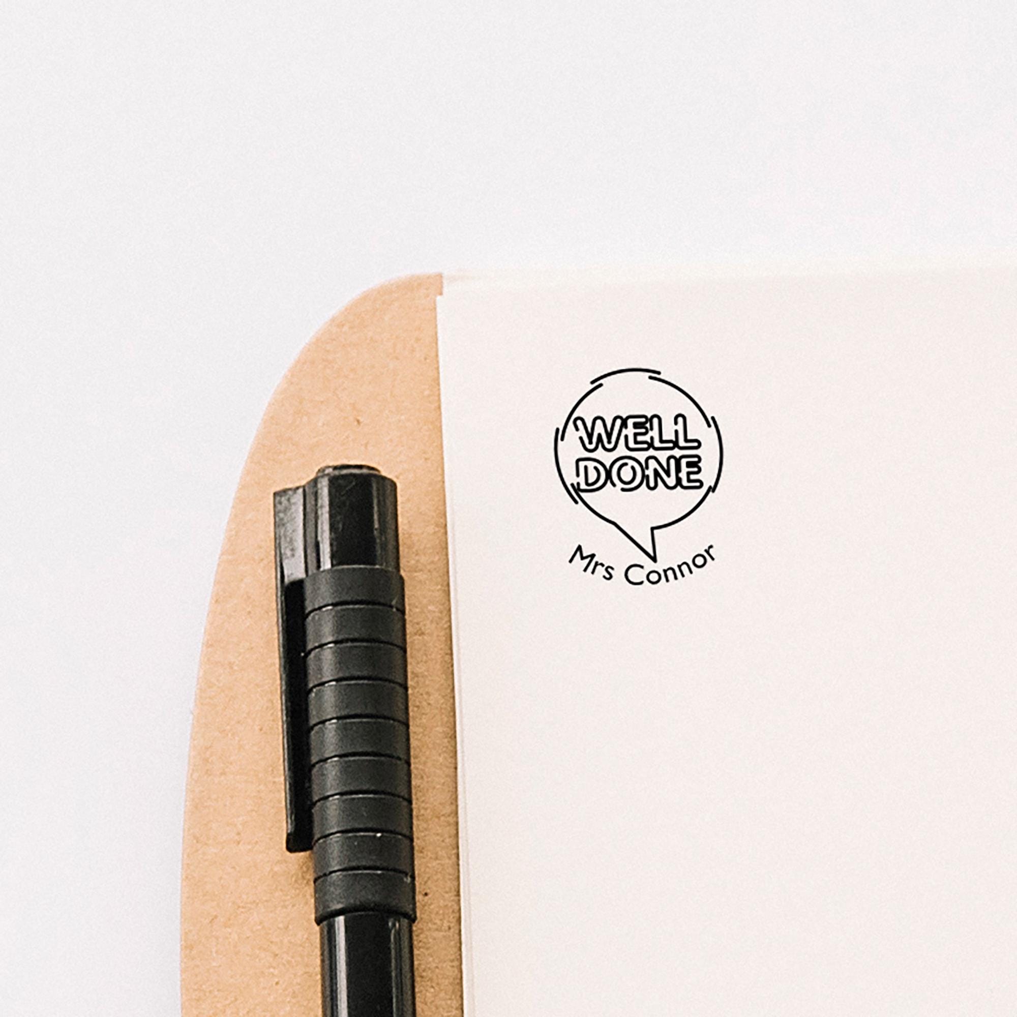 Custom teacher stamp displaying "WELL DONE" and "Mrs Connor" on a clipboard with a pen, ideal for motivating students.