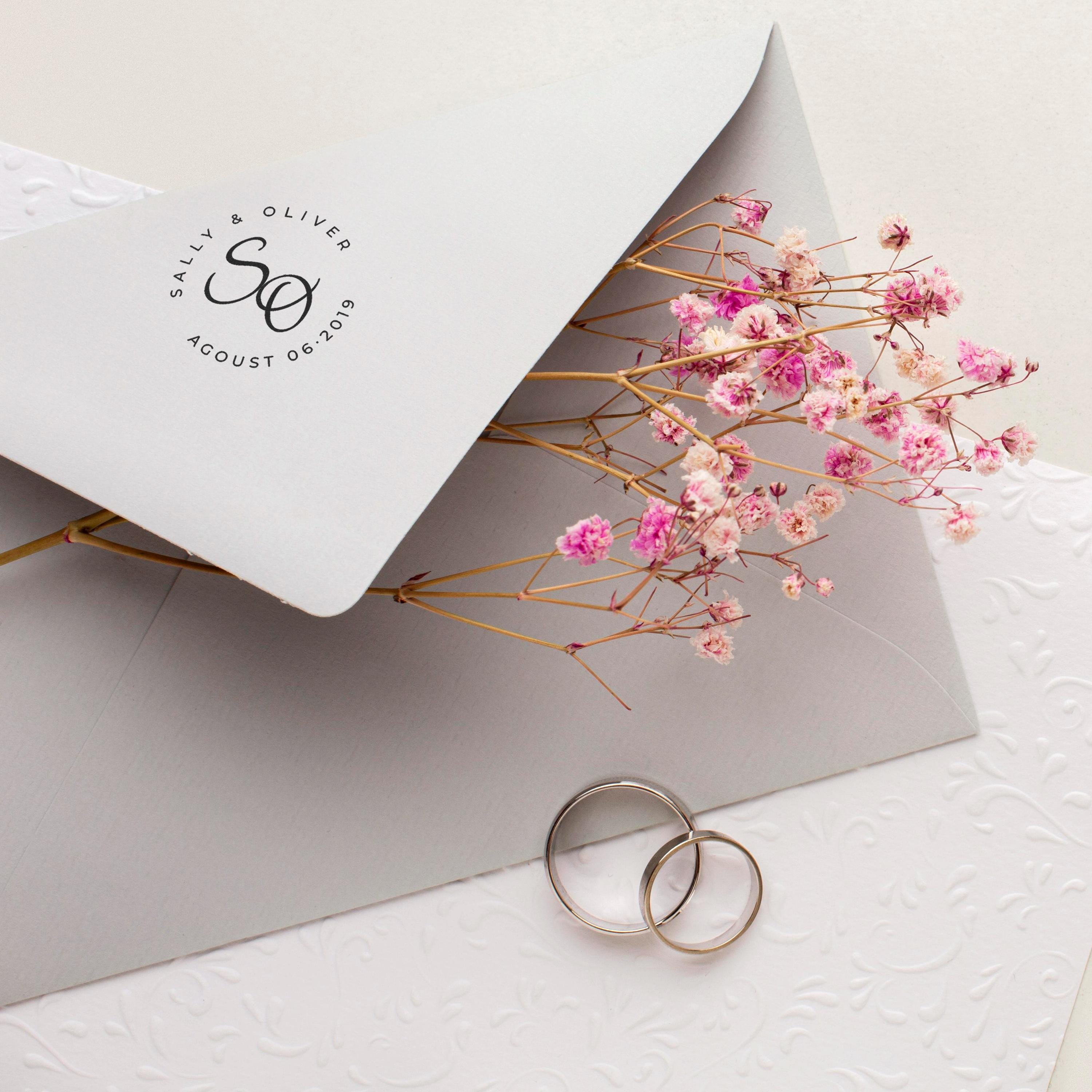 Wedding stamp on an envelope with dried flowers and two rings, showcasing elegant wedding stationery.