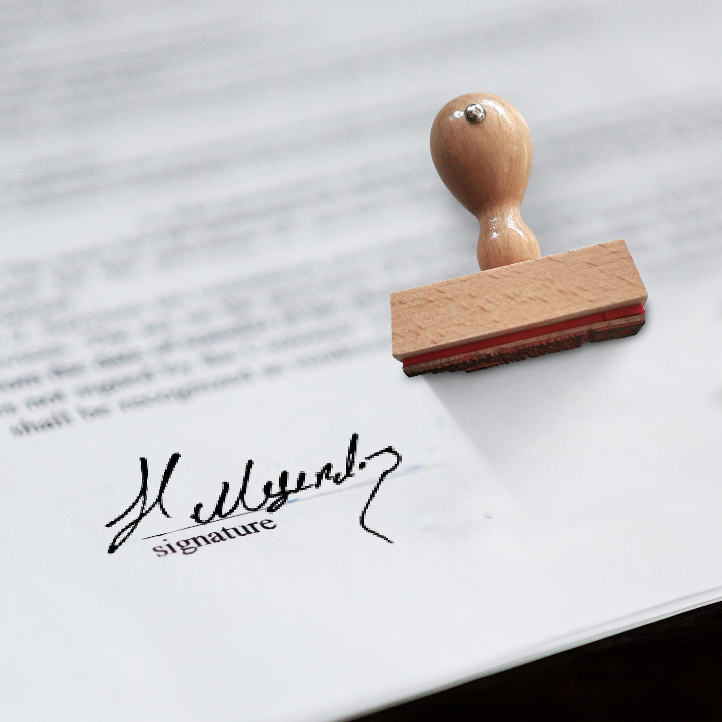 Custom signature stamp on document, showcasing personalized handwriting with wooden handle.