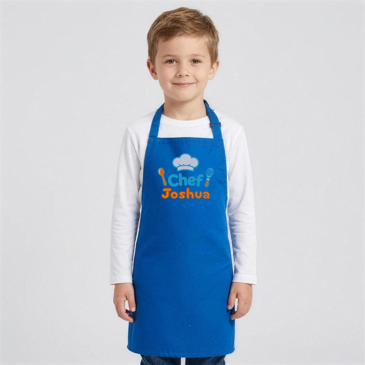 Boy wearing a royal blue Little Chef kids apron embroidered Chef Joshua