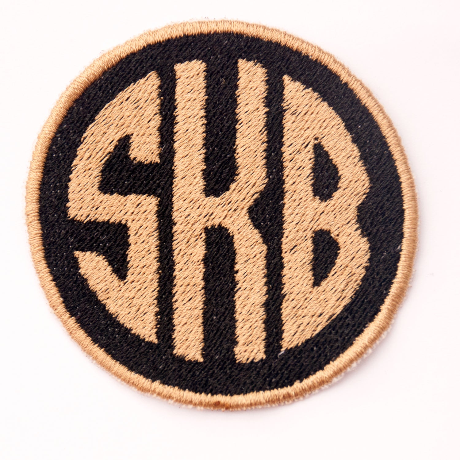 Personalised embroidered circle monogram patch with initials SKB in black and beige, 6cm size, available for sew-on or iron backing.