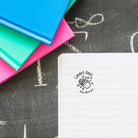 Custom Teacher Stamp on lined paper with colorful notebooks, personalized gift for classroom use.