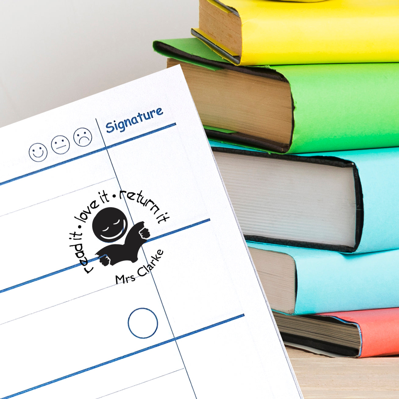 Custom teacher stamp on a book signing sheet next to colorful classroom books, perfect for personalized libraries.
