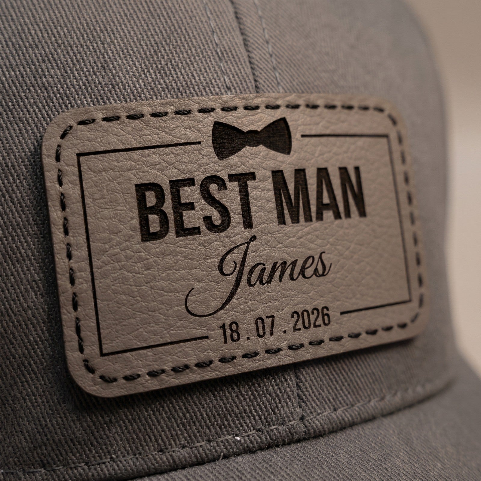 Macro close-up of the engraved leather patch showing black hand stitching and recessed engraving