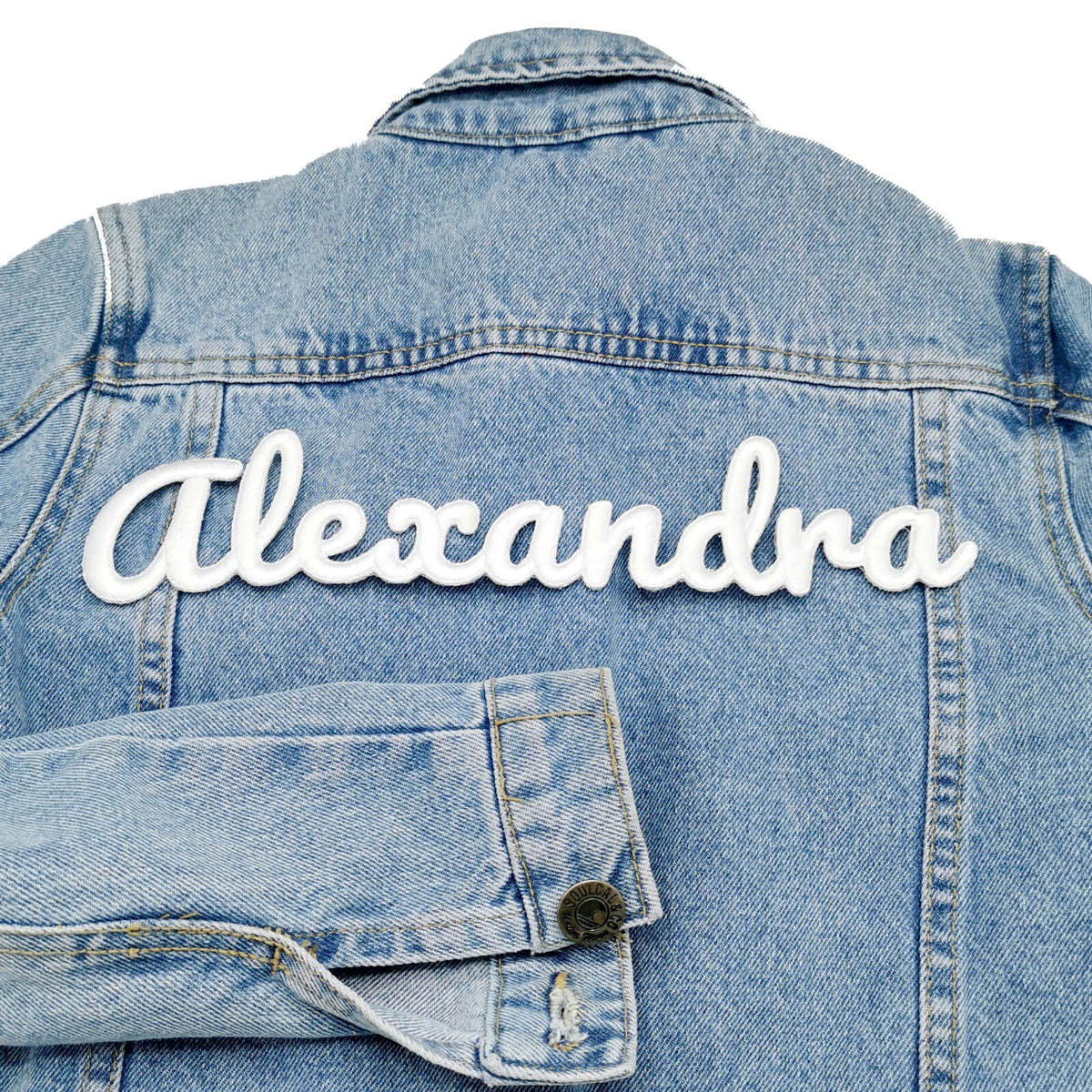 White 3D name patch reading Alexandra on the back of a denim jacket