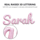Close-up of a pink 3D name patch showing the raised padded lettering and satin-stitched edge