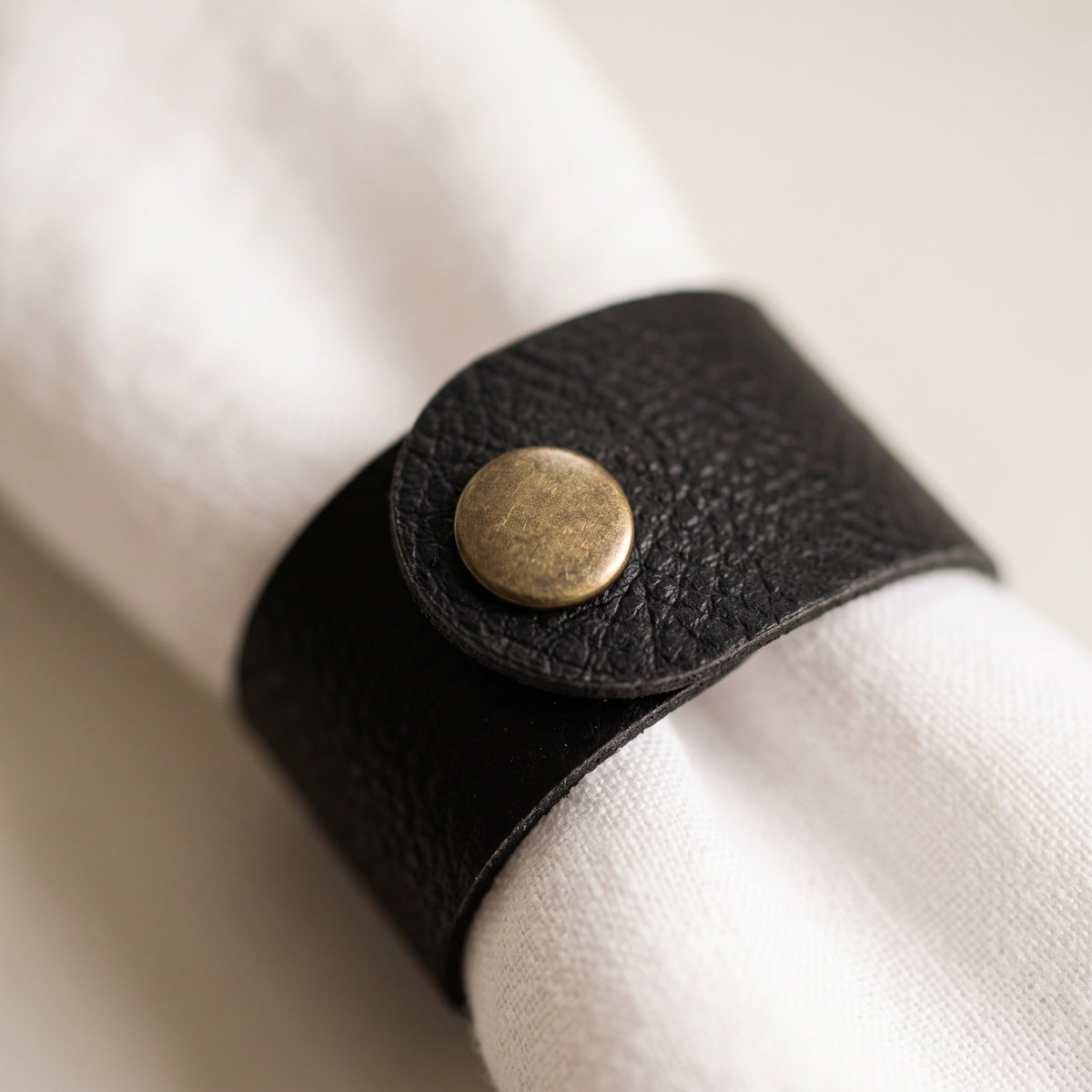 Close-up of the antique brass-colour press stud fastening the band around a white napkin