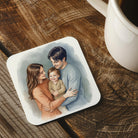 A family portrait of a man, woman, and child is displayed on a coaster, with a white mug visible in the background.