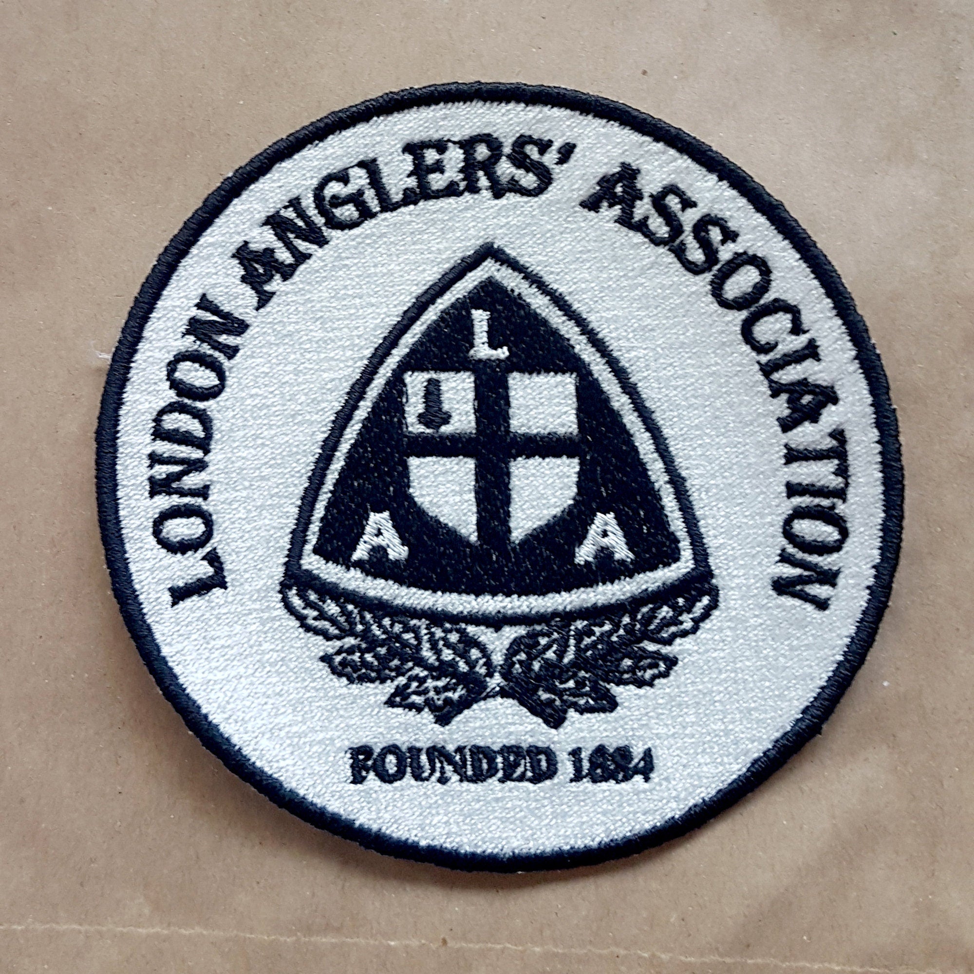 London Anglers' Association embroidered patch, circular design with established date 1884, detailed logo in black and white.