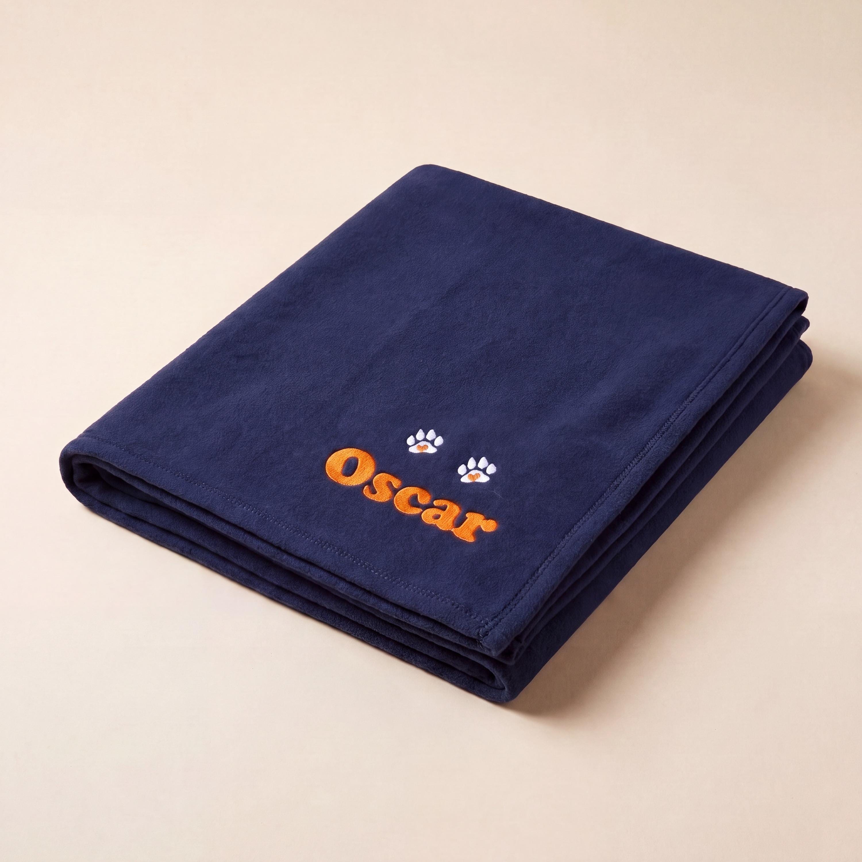 Three quarter view of folded personalised dog blanket with embroidered name