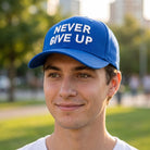 Man wearing a bright royal blue custom cap with NEVER GIVE UP in white 3D puff embroidery