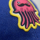 Macro close-up of a dye-sublimation printed patch with a flat satin-stitch die-cut edge on the cap fabric