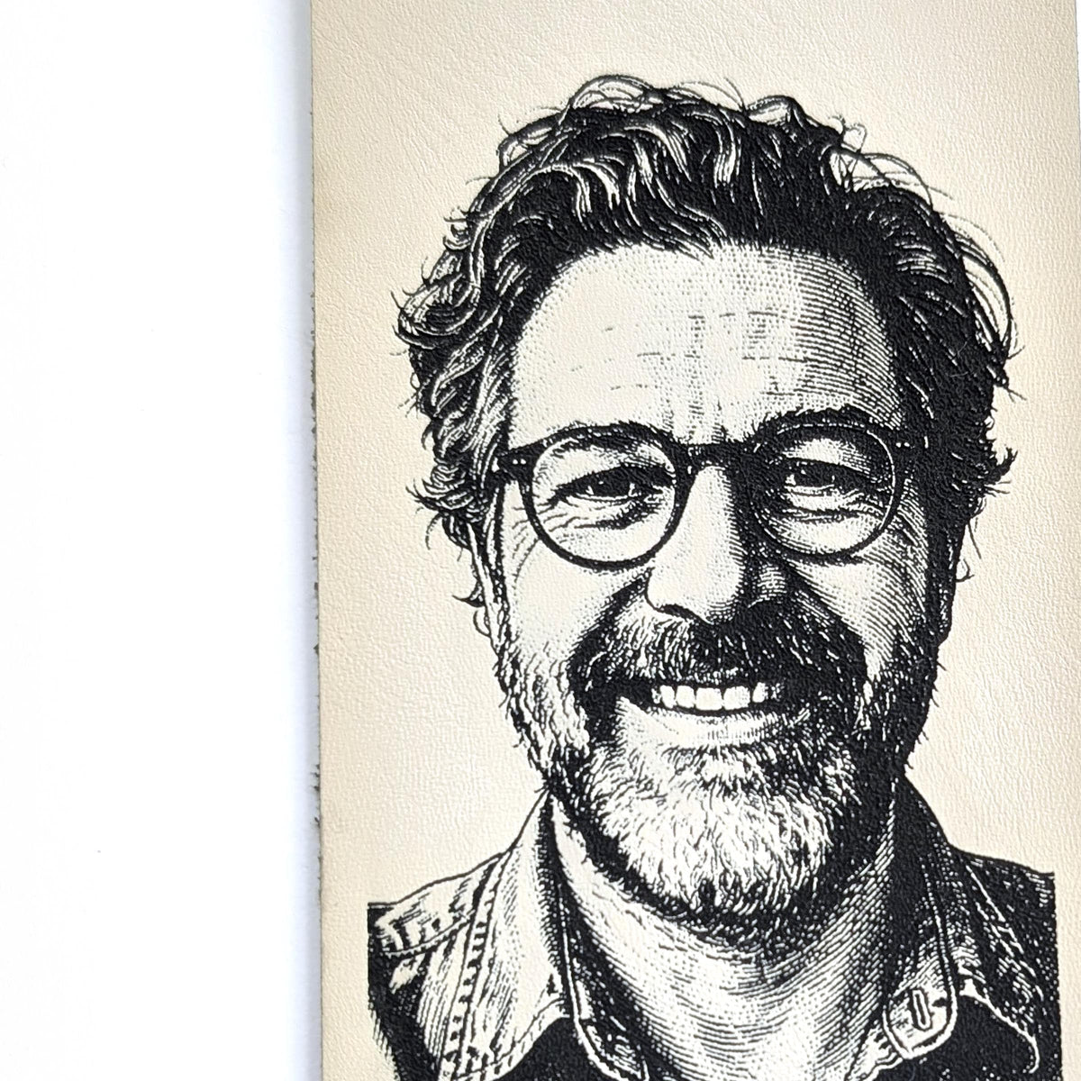 Close-up of a laser engraved portrait on cream vegan leather, showing fine line detail