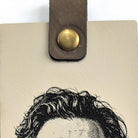 Close-up of the tab and metal snap at the top of the cream vegan leather bookmark