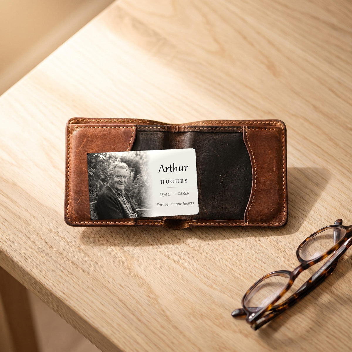 Memorial wallet card inside an open leather wallet beside reading glasses