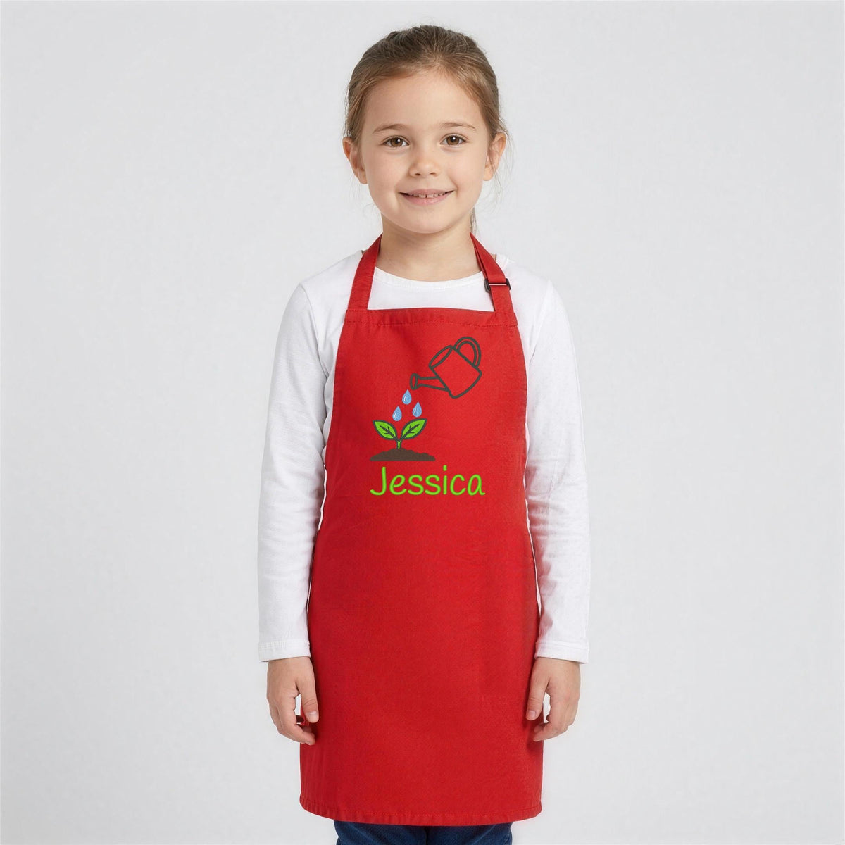 Girl in a red children's apron embroidered with a watering can and the name Jessica